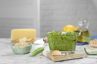 Delicious pesto sauce and ingredients on white marble table. Space for text