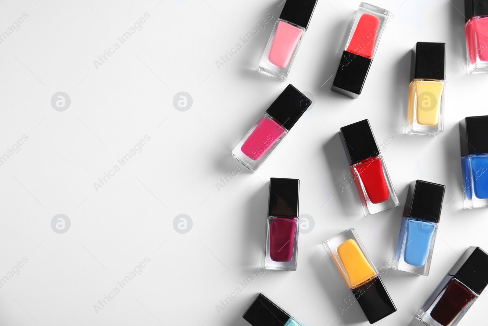 Photo of Bottles of bright nail polish on white background, top view