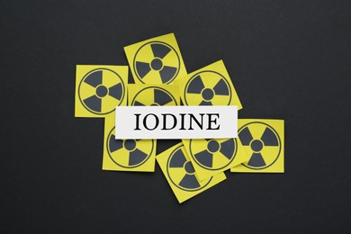 Photo of Paper note with word Iodine and radiation signs on black background, flat lay