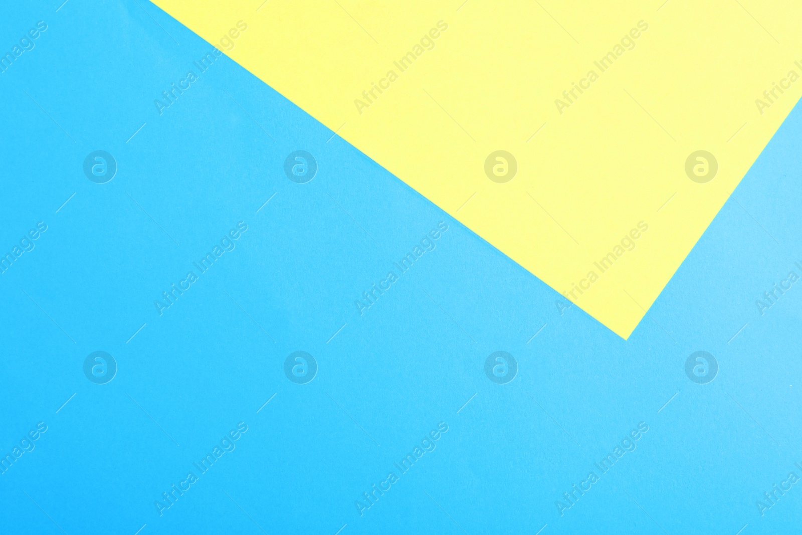 Photo of Blue and yellow paper sheets as colorful background, top view