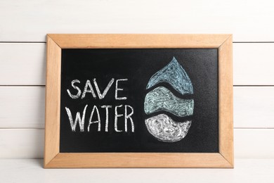 Photo of Blackboard with words Save Water and drop on white wooden table, top view