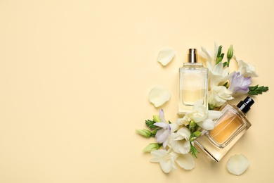 Photo of Flat lay composition with different perfume bottles and freesia flowers on yellow background, space for text