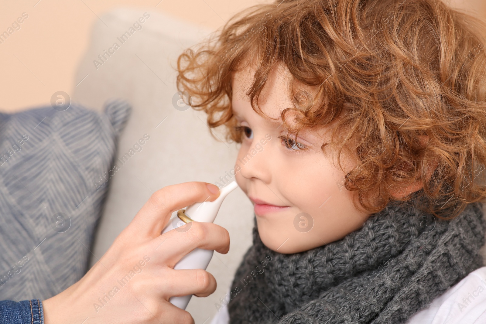 Photo of Mother using nasal spray to treat her little son indoors, closeup