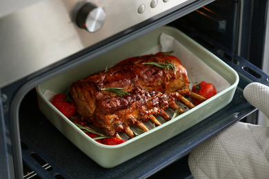 Chef taking delicious roasted ribs out of oven, closeup