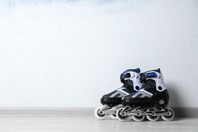Photo of Inline roller skates on floor near color wall. Space for text