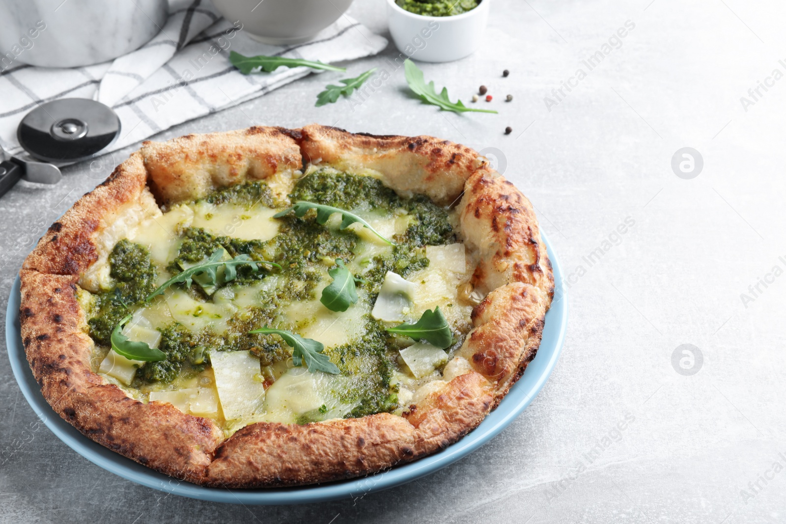 Photo of Delicious pizza with pesto, cheese and arugula on grey table