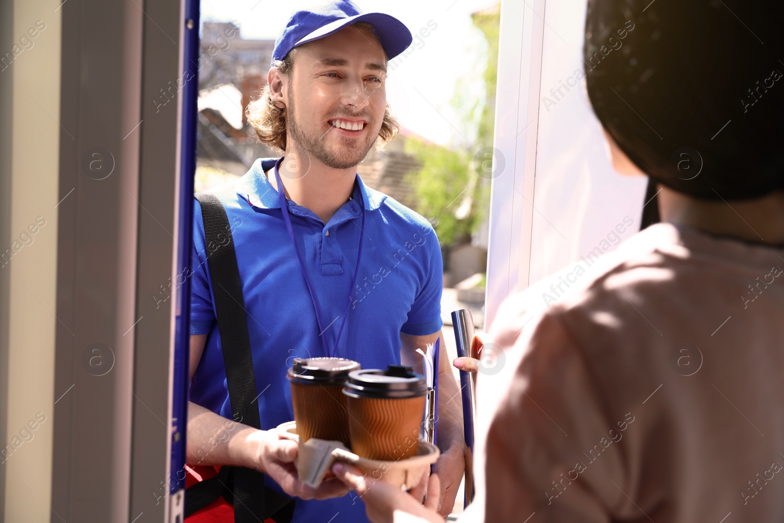 Photo of Woman receiving order from courier at door. Food delivery service