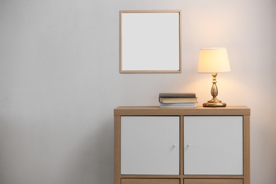 Image of Stylish cabinet near wall with empty poster