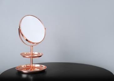 Modern mirror on table near color wall