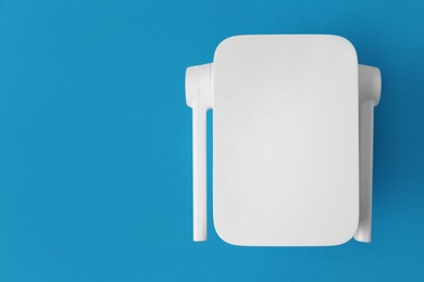 Photo of New modern Wi-Fi repeater on blue background, top view. Space for text