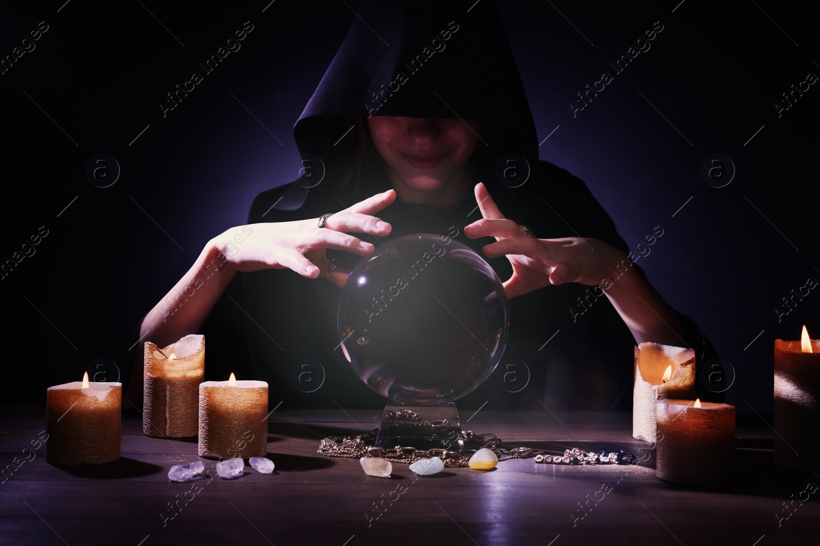 Photo of Soothsayer using crystal ball to predict future at table in darkness. Fortune telling