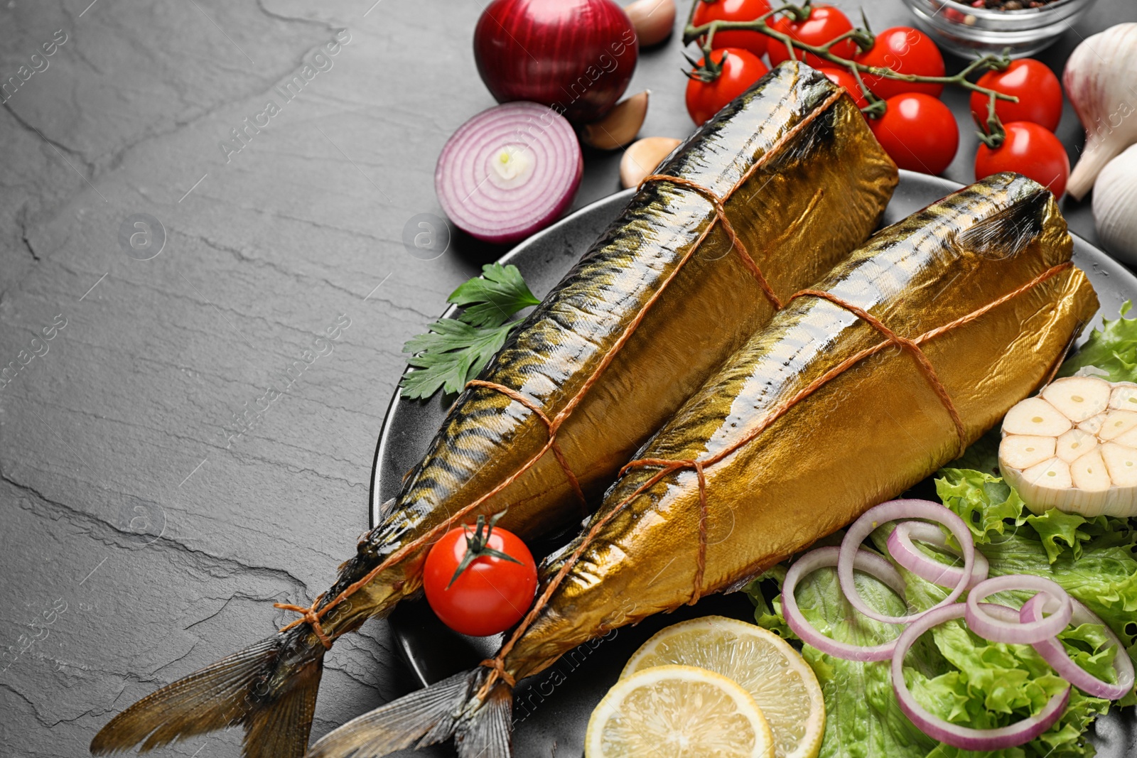 Photo of Tasty smoked fish served on dark table