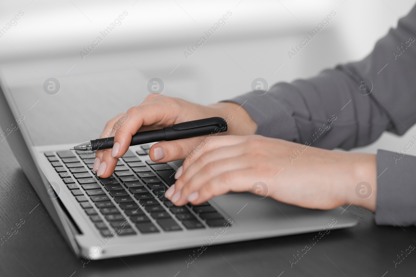Photo of Woman typing on laptop at table, closeup. Electronic document management