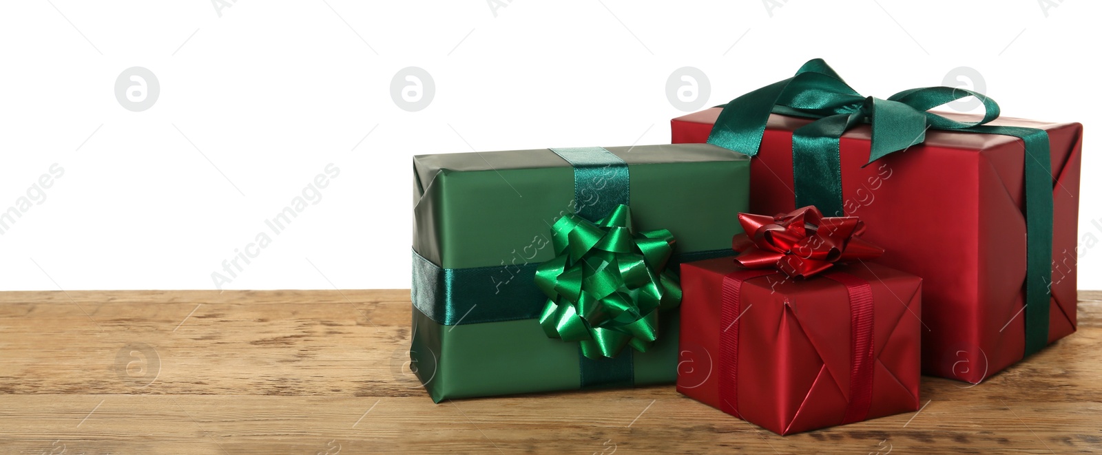 Photo of Red and green gift boxes on wooden table against white background, space for text