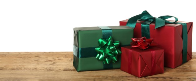 Red and green gift boxes on wooden table against white background, space for text