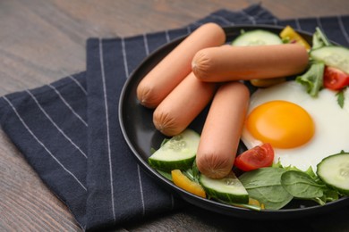 Photo of Delicious breakfast with boiled sausages and fried egg on wooden table, closeup