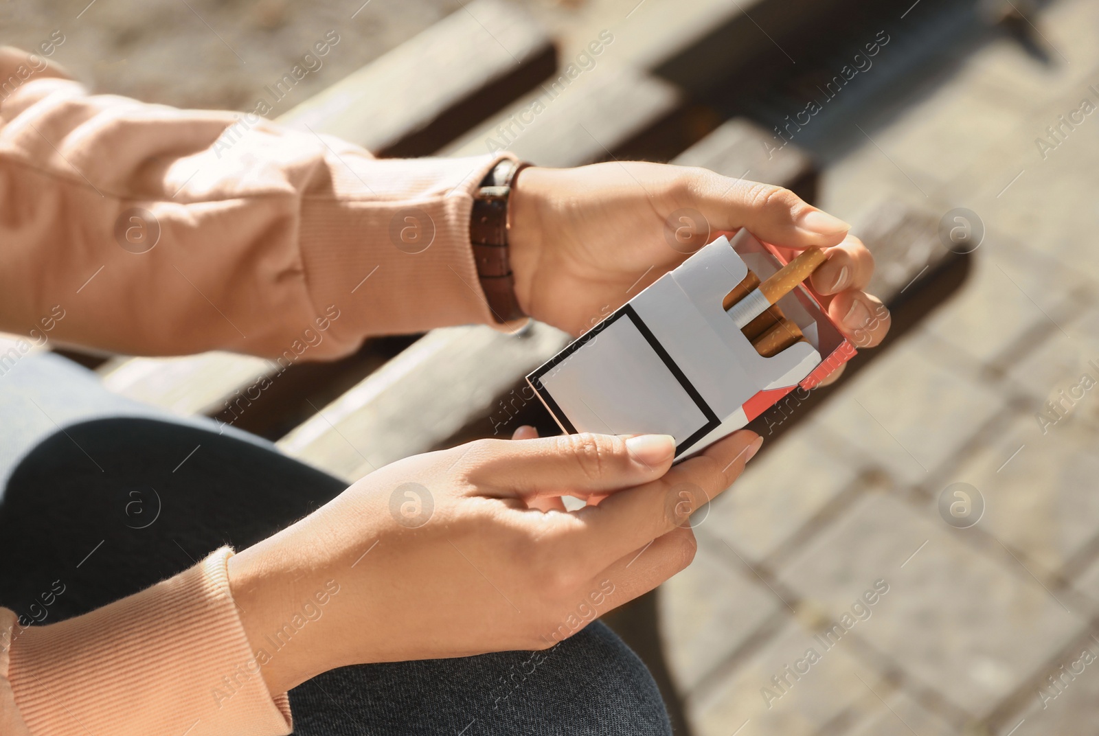 Photo of Woman taking cigarette out of pack outdoors, closeup