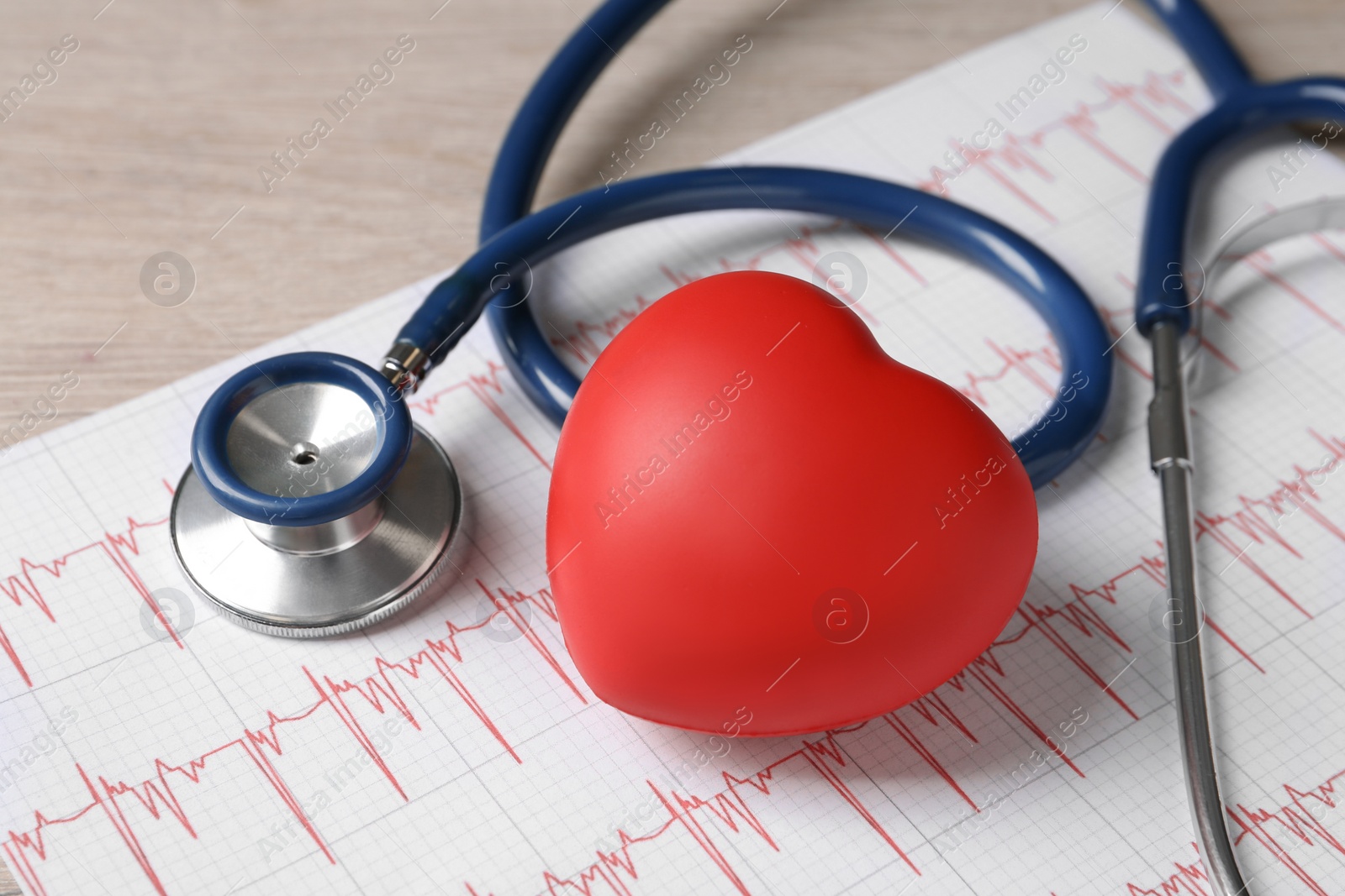 Photo of Stethoscope, cardiogram and red decorative heart on wooden background, closeup. Cardiology concept