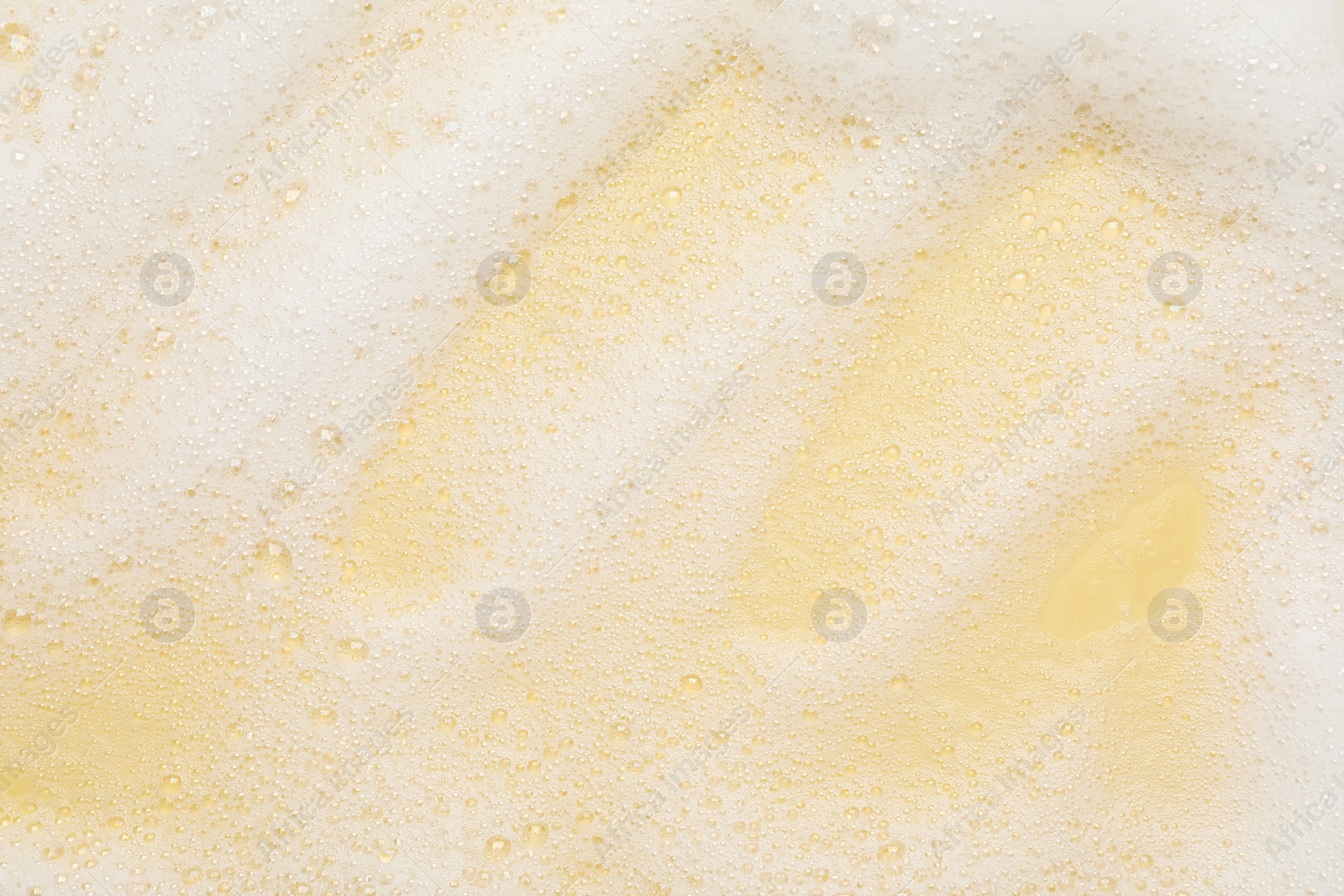 Photo of White washing foam on yellow background, top view