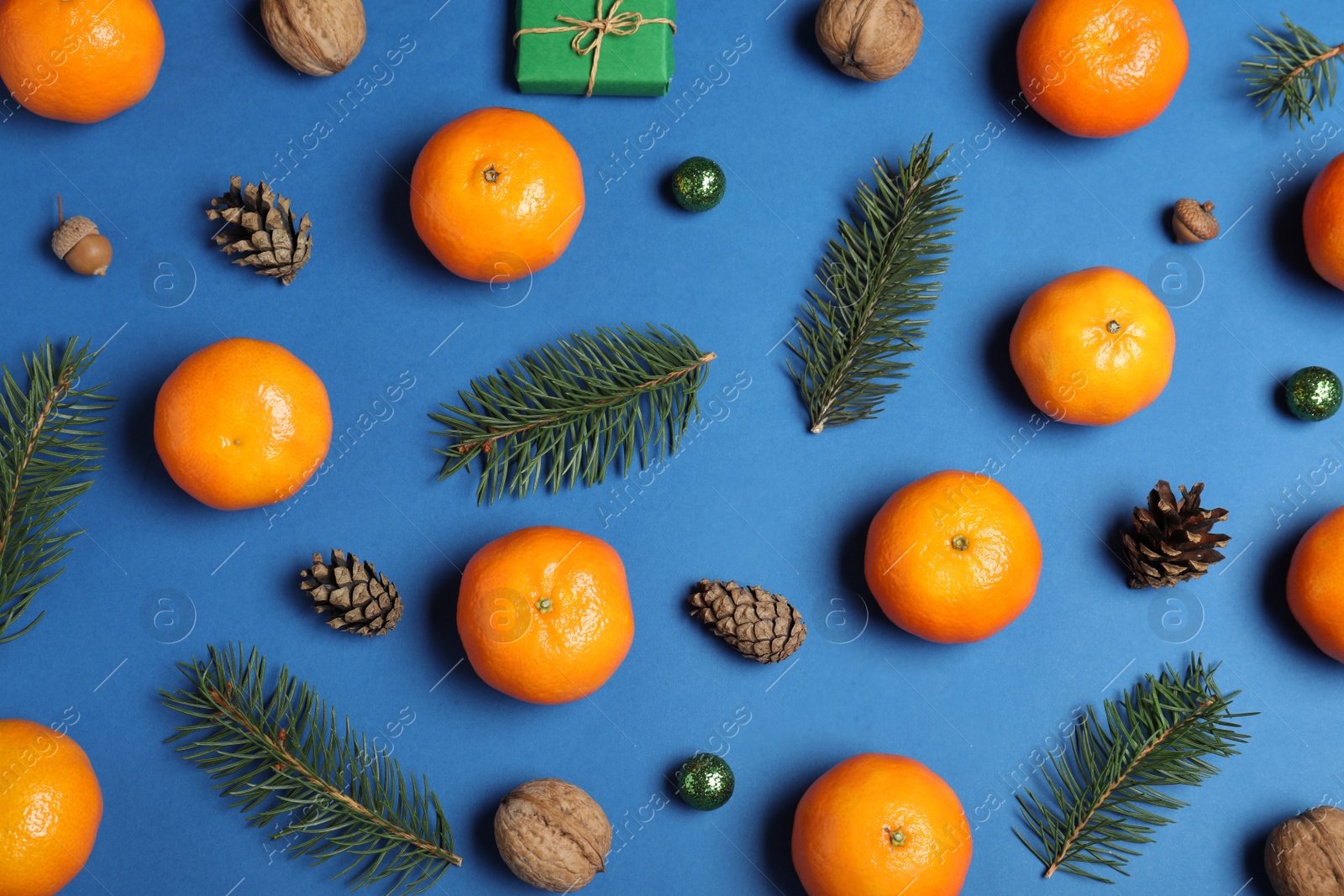 Photo of Flat lay composition with ripe tangerines, fir branches and Christmas decor on blue background