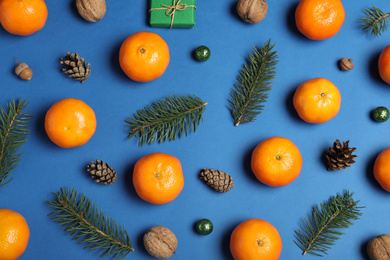 Flat lay composition with ripe tangerines, fir branches and Christmas decor on blue background