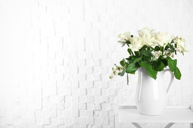 Photo of Vase with bouquet of beautiful flowers on table near brick wall. Space for text