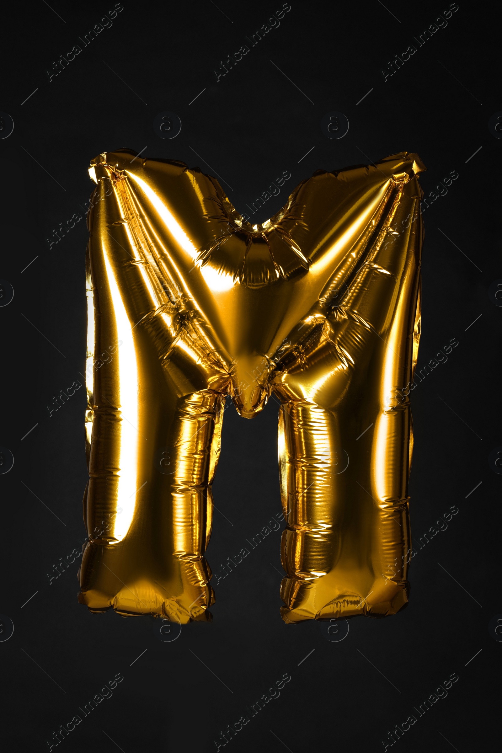 Photo of Golden letter M balloon on black background