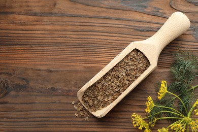 Photo of Scoop of dry seeds and fresh dill on wooden table, flat lay. Space for text