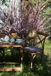 Photo of Beautiful spring flowers, freshly baked waffles and ripe strawberries on table served for tea drinking in garden