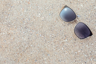 Photo of Stylish sunglasses on sandy beach, top view. Space for text