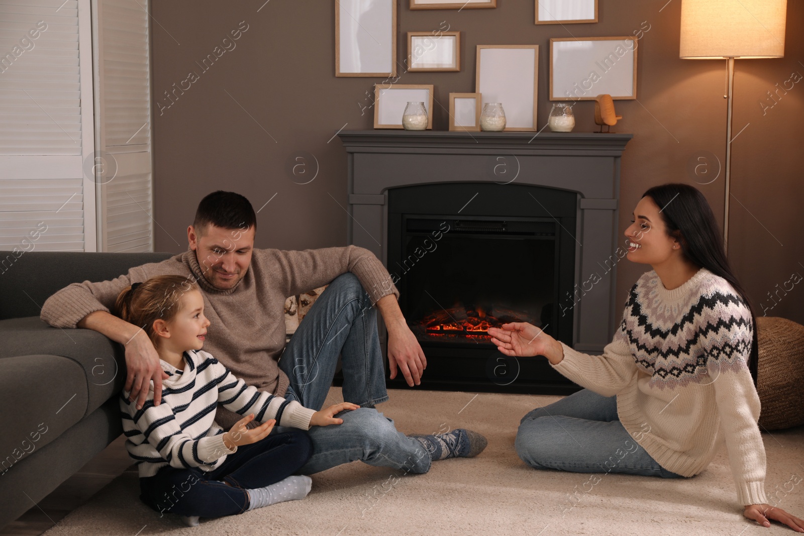 Photo of Happy family spending time together near fireplace at home