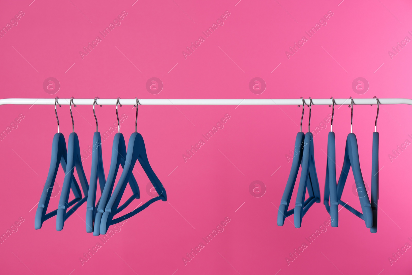 Photo of Metal rack with clothes hangers on color background