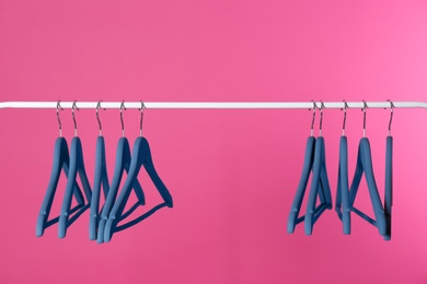 Photo of Metal rack with clothes hangers on color background