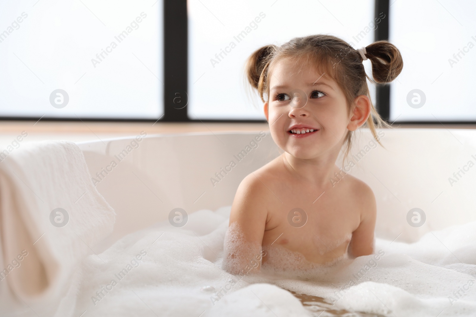 Photo of Cute little girl taking bubble bath at home