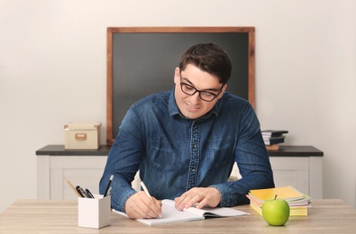 Photo of Portrait of male teacher sitting at table in classroom