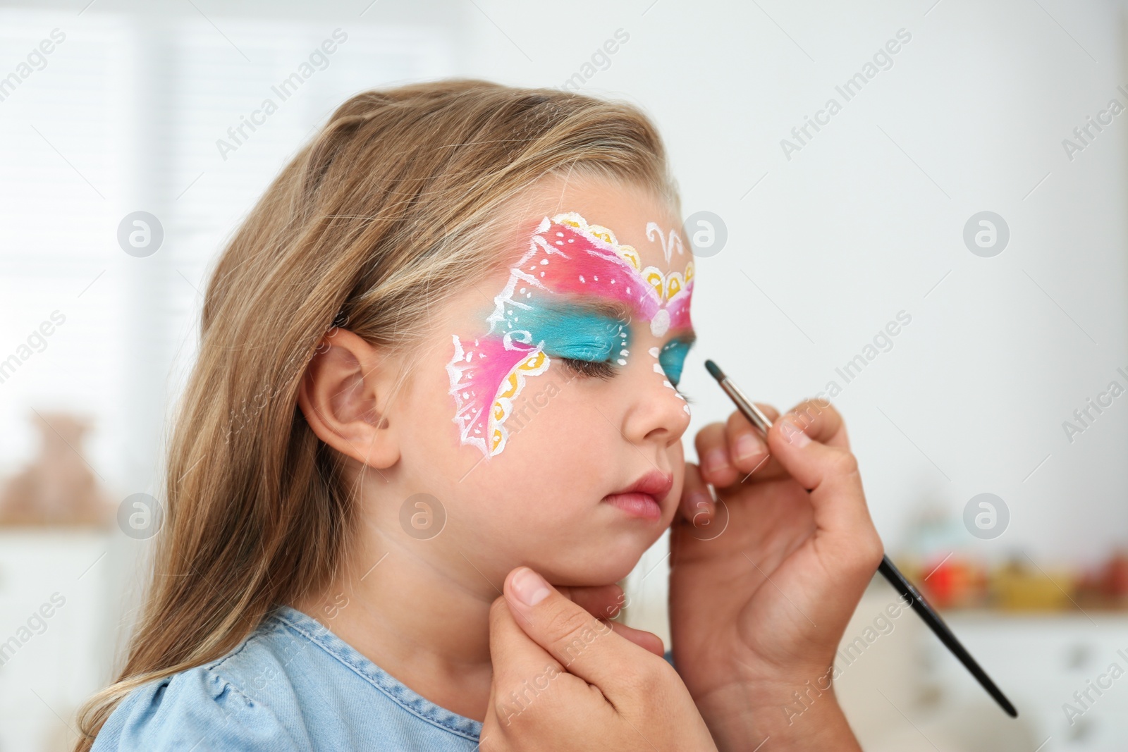 Photo of Artist painting face of little girl indoors