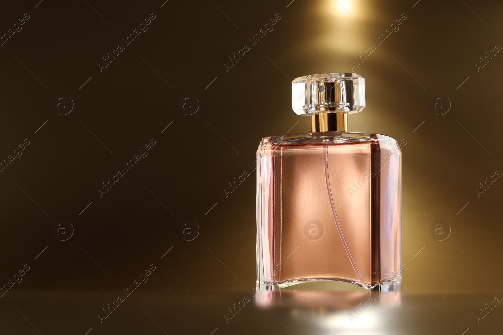 Photo of Luxury women's perfume. Sunlit glass bottle on golden background, space for text