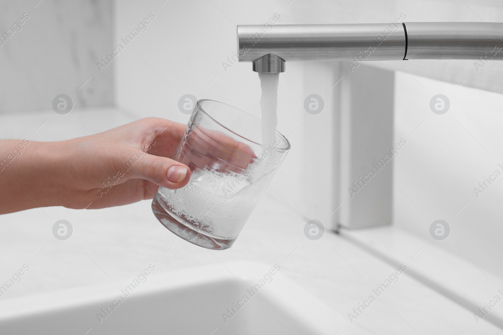 Photo of Woman filling glass with water from tap in kitchen, closeup