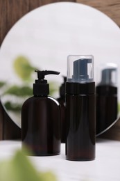 Photo of Different face cleansing products near mirror on white table