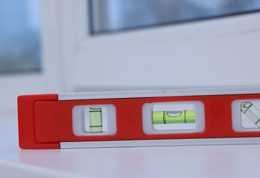 Photo of Red building level on white windowsill indoors, closeup