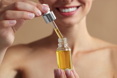 Photo of Woman with cosmetic serum in her hands on beige background, closeup