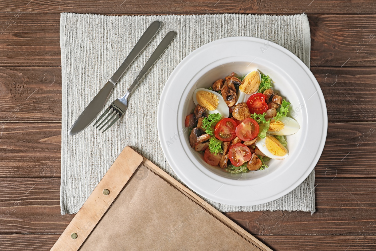 Photo of Plate with delicious fresh salad and menu on table, top view