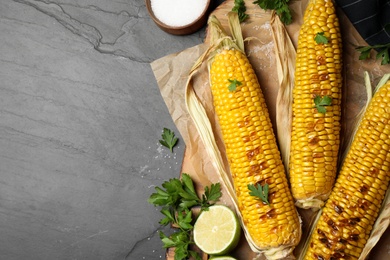 Tasty grilled corn on black table, flat lay. Space for text