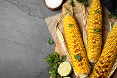 Photo of Tasty grilled corn on black table, flat lay. Space for text