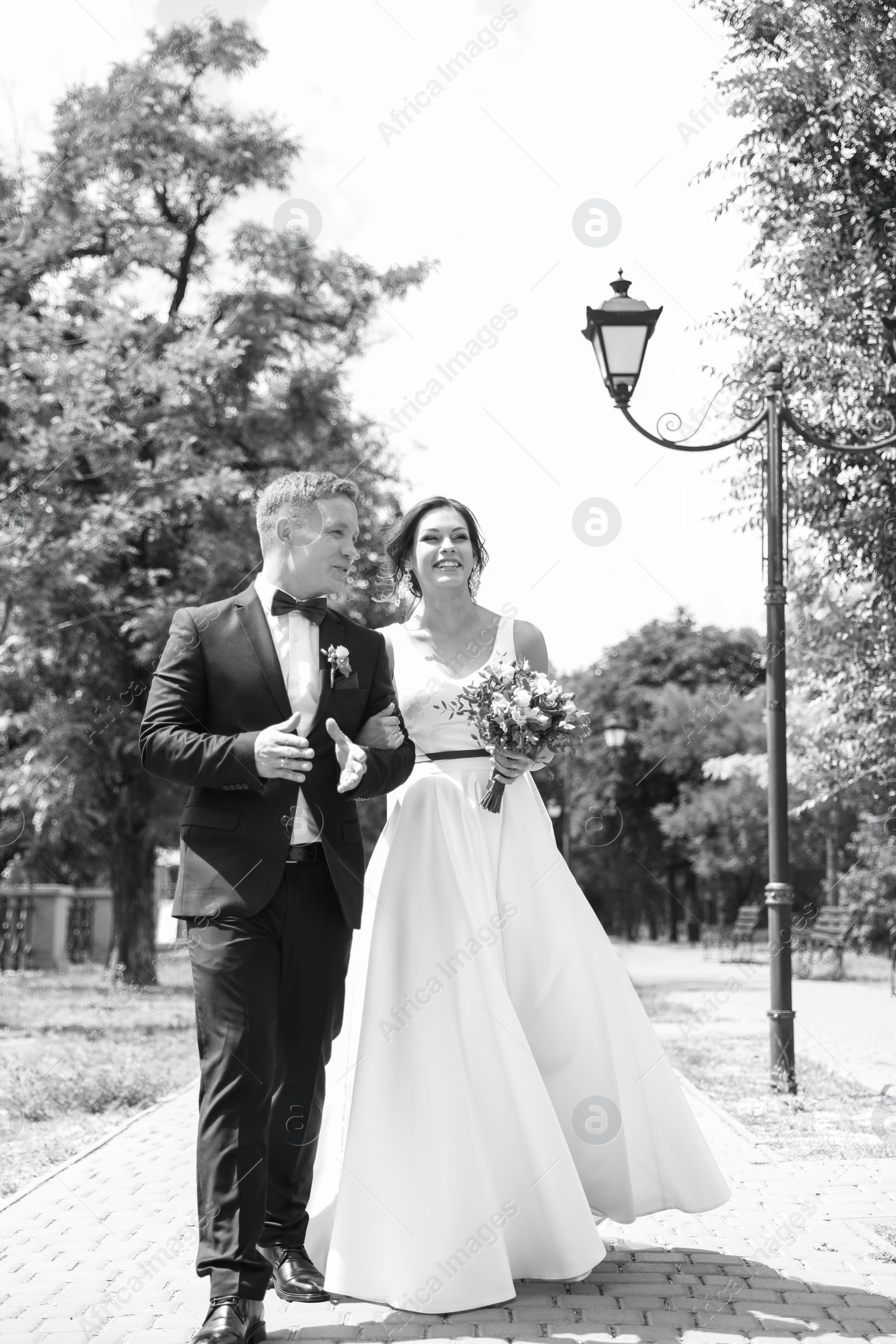 Photo of Happy newlyweds walking outdoors, black and white effect
