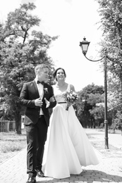 Photo of Happy newlyweds walking outdoors, black and white effect