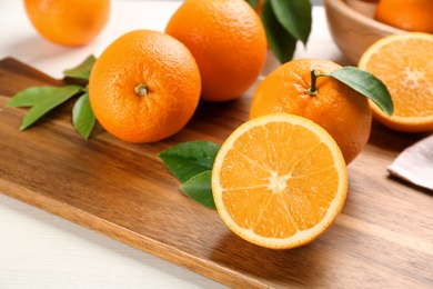 Photo of Many delicious ripe oranges on wooden board