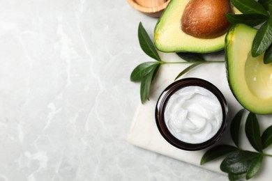 Photo of Jarface cream and avocado on marble table, flat lay. Space for text