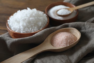 Photo of Different types of organic salt on wooden table, closeup