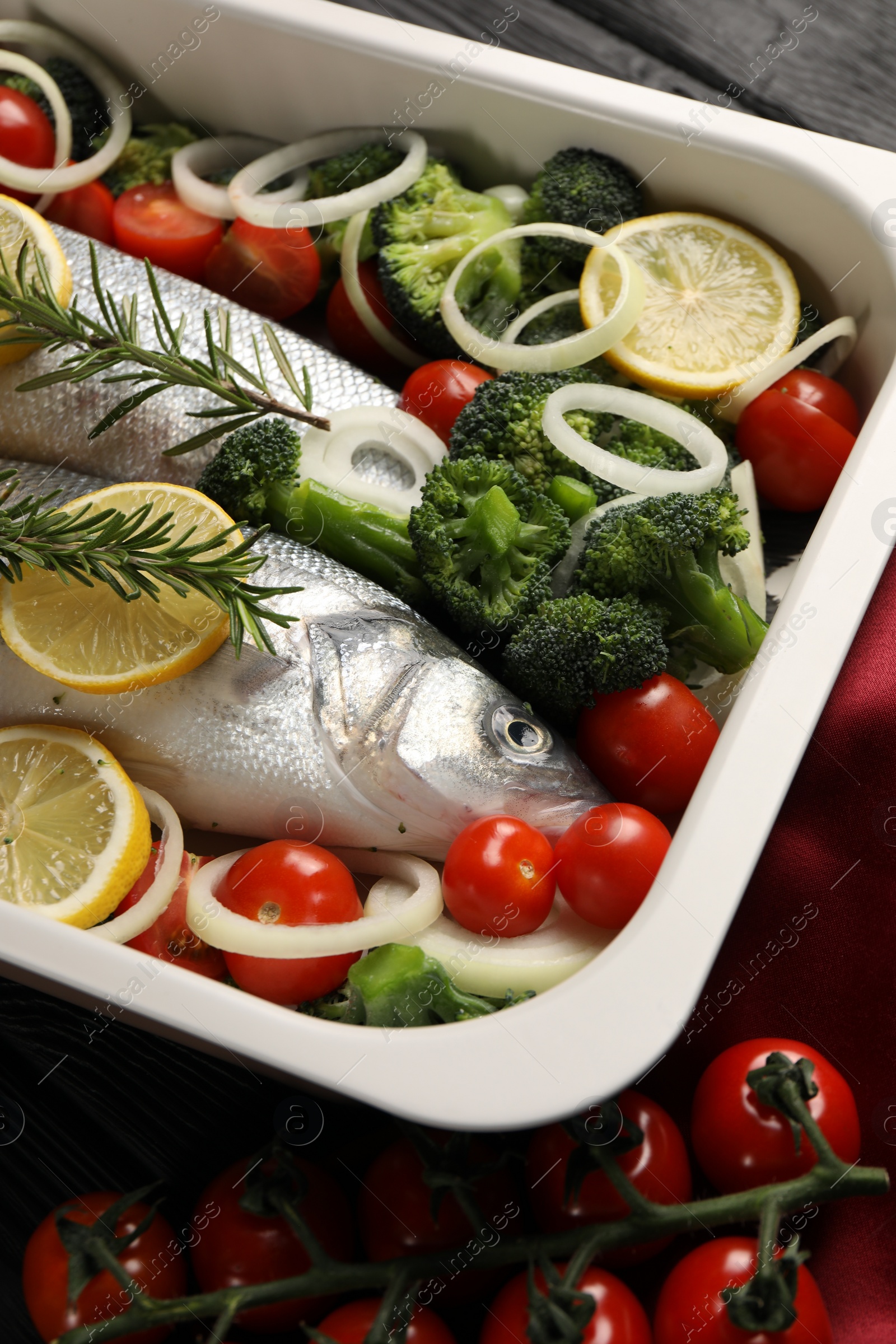 Photo of Raw fish with vegetables and lemon in baking dish on table